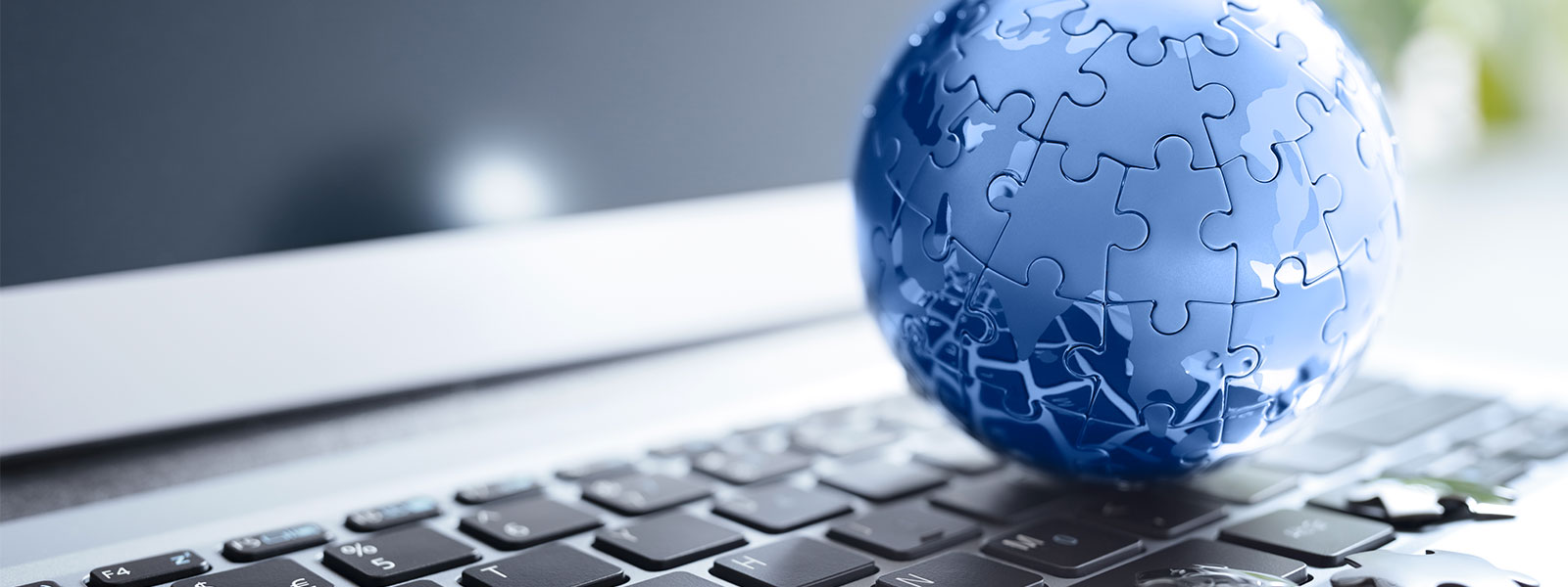Blue puzzle-piece globe resting on a laptop keyboard